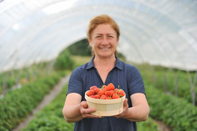 Christelle debout sous la serre présente ses fraises