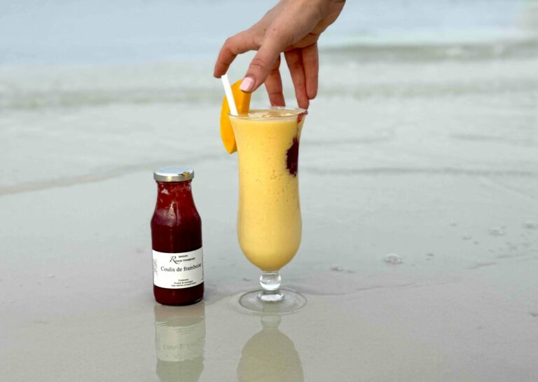 Verre à cocktail et coulis de framboise sur la plage