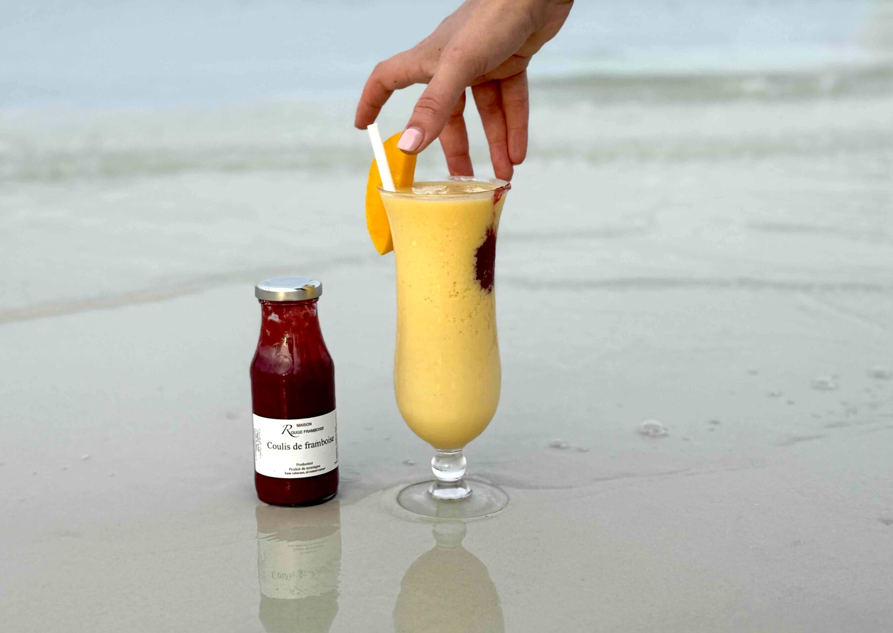 Verre à cocktail et coulis de framboise sur la plage